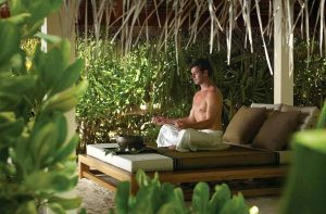 A man meditating at an yoga retreat and feeling relaxed.